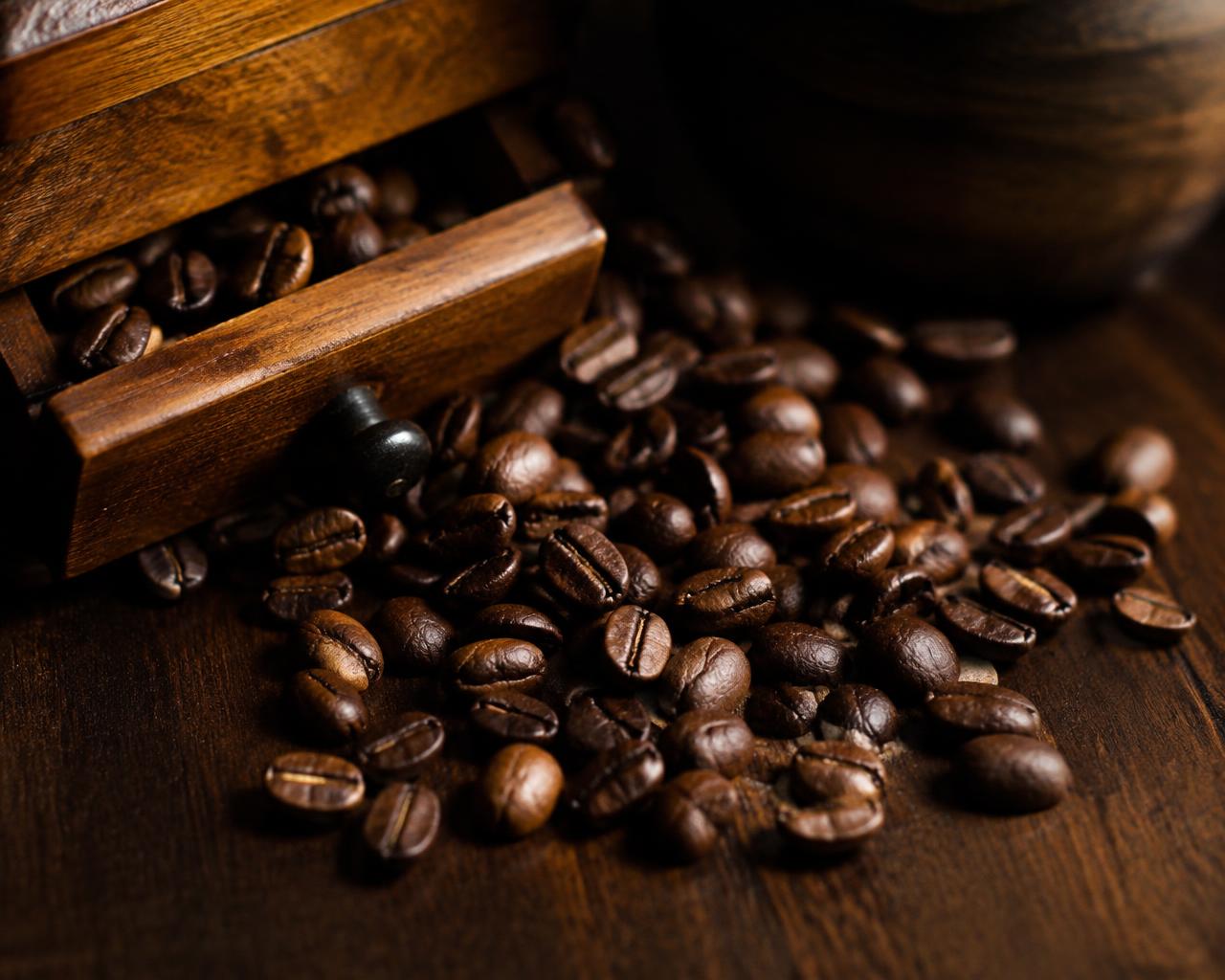 Roasted coffee beans spilling from a hand grinder (illustrative)